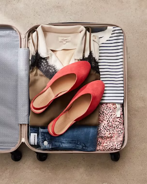 Open suitcase with basic clothes and red flats – perfect for packing based on trip length and destination