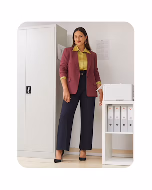 Woman in an office wearing a burgundy blazer, satin shirt and navy straight-leg trousers with black heels – inspiration for back-to-work 2025.