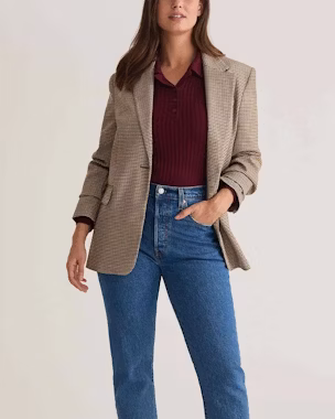 Woman in business casual look: tweed blazer, dark red knit polo and blue jeans