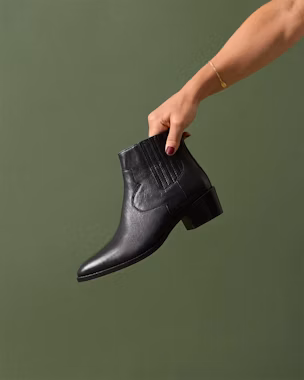 Close-up of a black leather ankle boot with pointed toe and low heel, a versatile shoe for outfits with jeans or dresses.