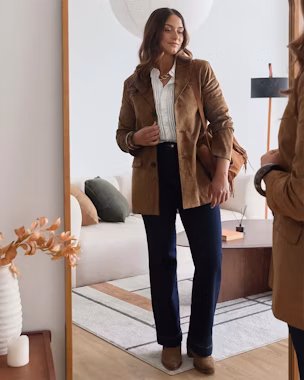 Outfit smart casual da donna con blazer in suede marrone su camicia bianca, jeans dritti scuri e stivaletti color cammello; look rilassato dall’ufficio al weekend.