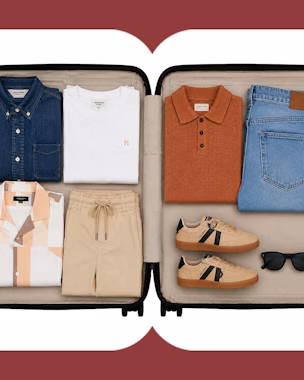 Vista aérea de una maleta de mano bien organizada con básicos masculinos versátiles como chinos, una camisa impecable y prendas de entretiempo. Una disposición que prioriza la eficiencia y el estilo, perfecta para el viajero moderno.