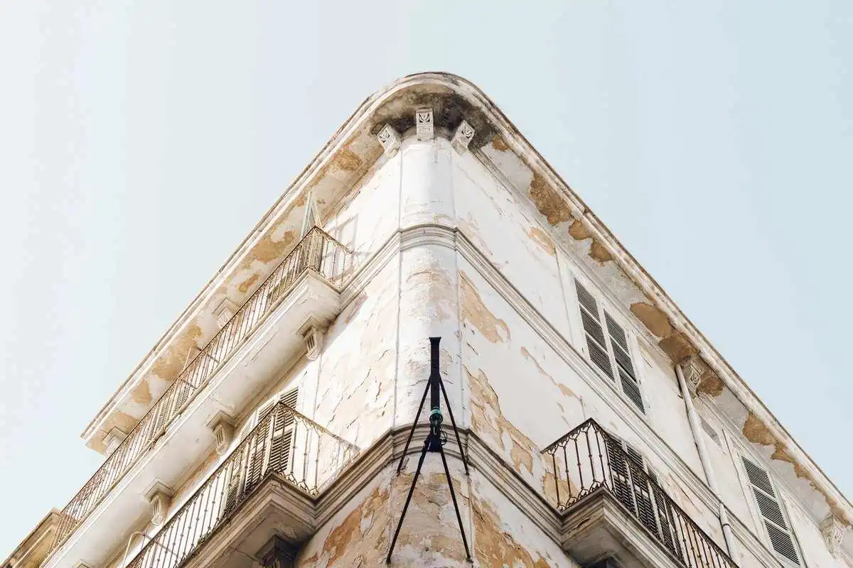 Façade d'un immeuble ancien avec balcons nécessitant une rénovation et des travaux de ravalement pour de l'investissement locatif