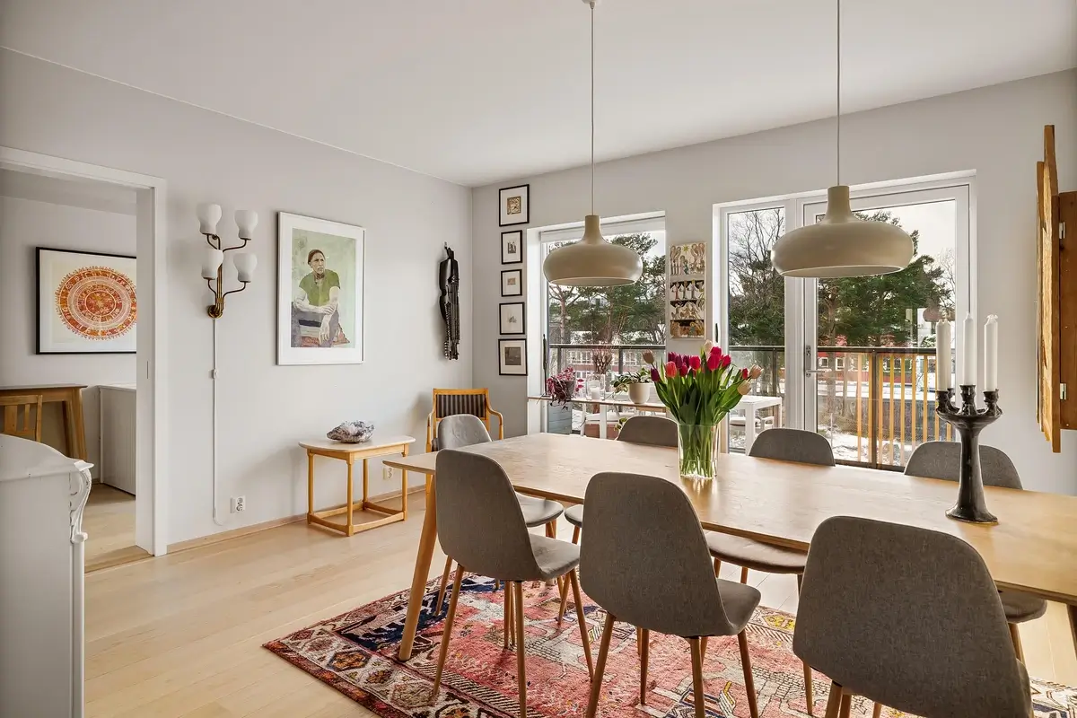 Grande salle à manger lumineuse d'un appartement meublé de standing avec table en bois, chaises modernes et décoration soignée pour un investissement en location meublée (LMNP / LMP).