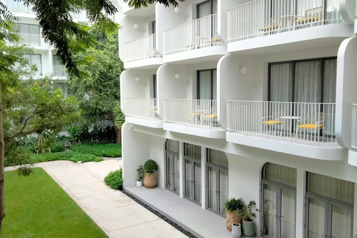 Façade blanche et moderne d'une résidence de services neuve avec balcons, donnant sur un jardin verdoyant, idéale pour investir en LMNP géré.