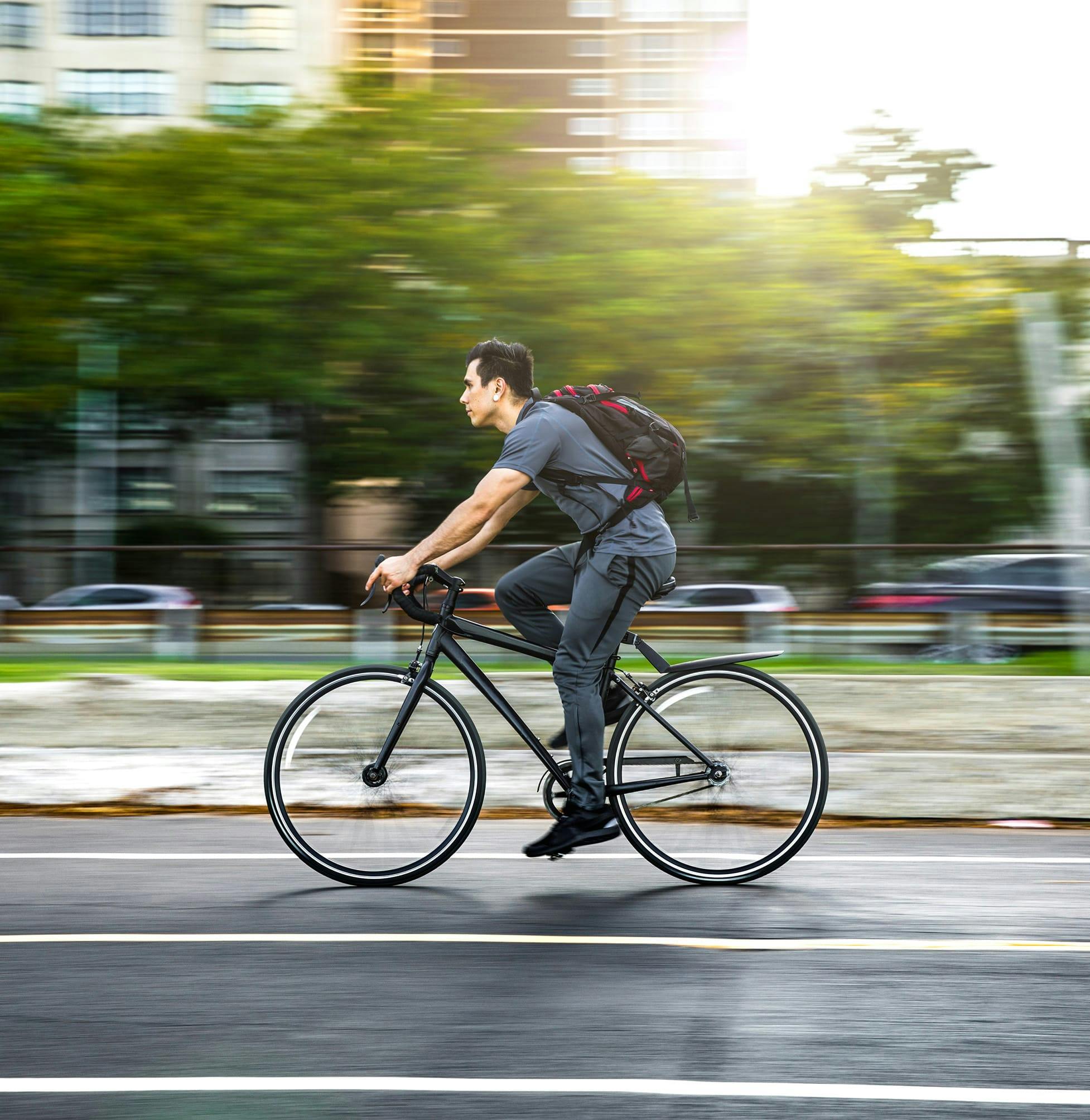 there is a man riding a bike down the street with a backpack on