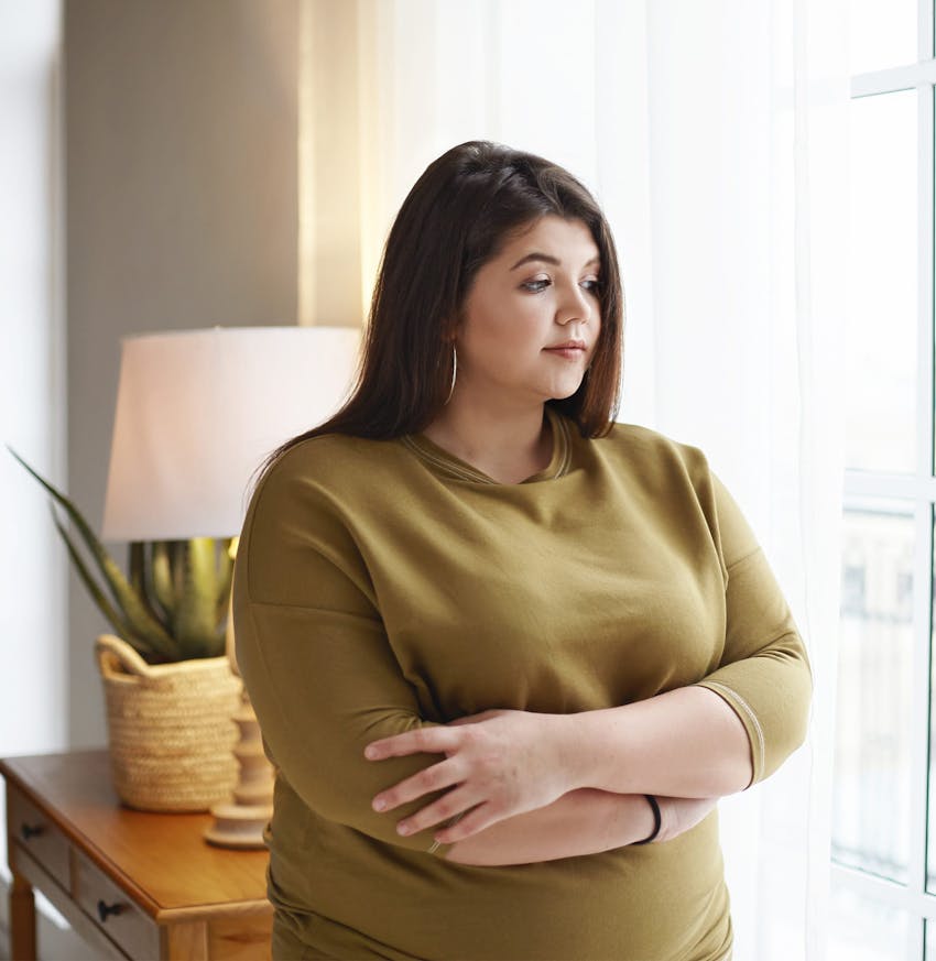 there is a woman standing by a window with her arms crossed