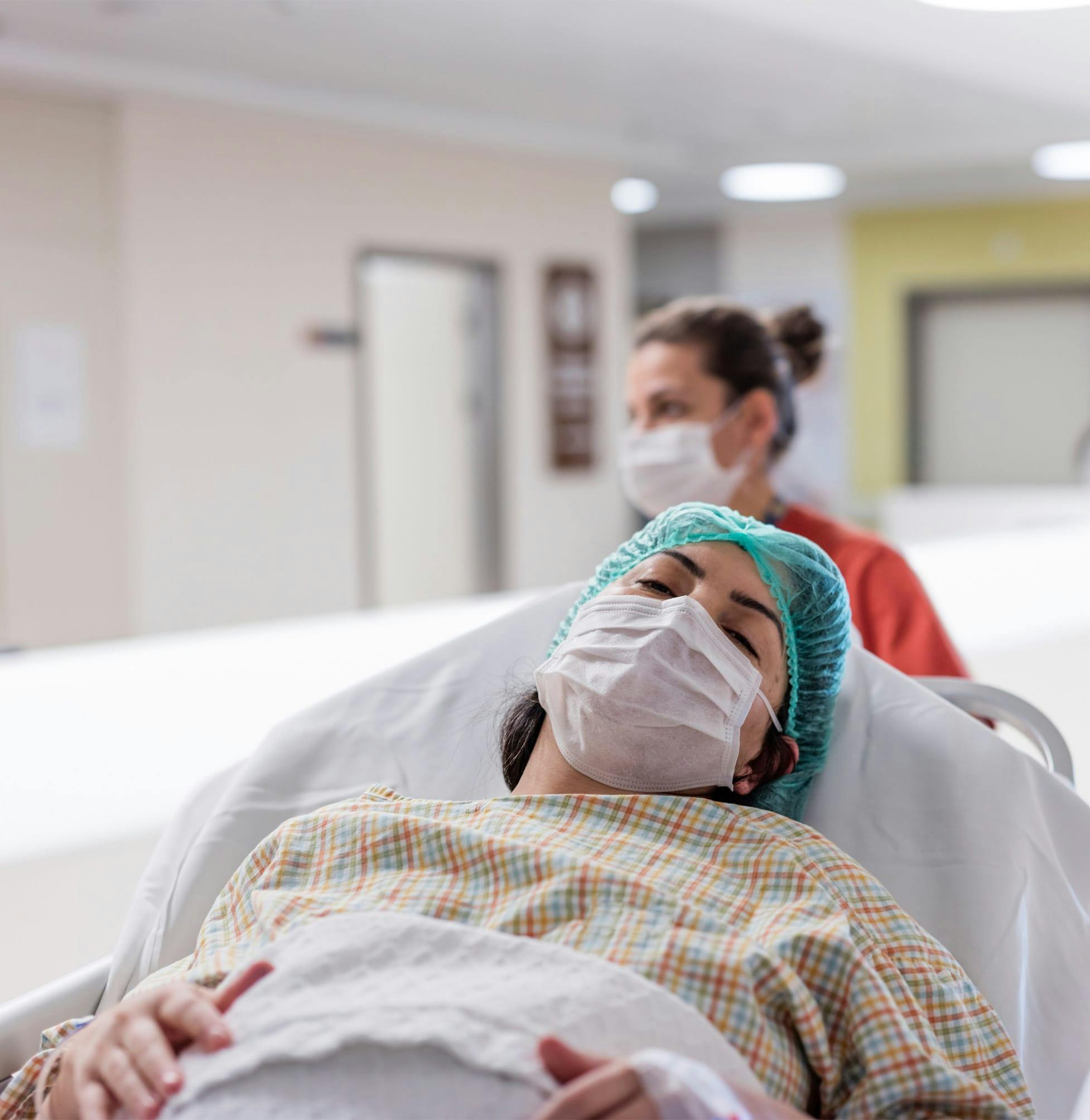 there is a woman laying in a hospital bed with a face mask on