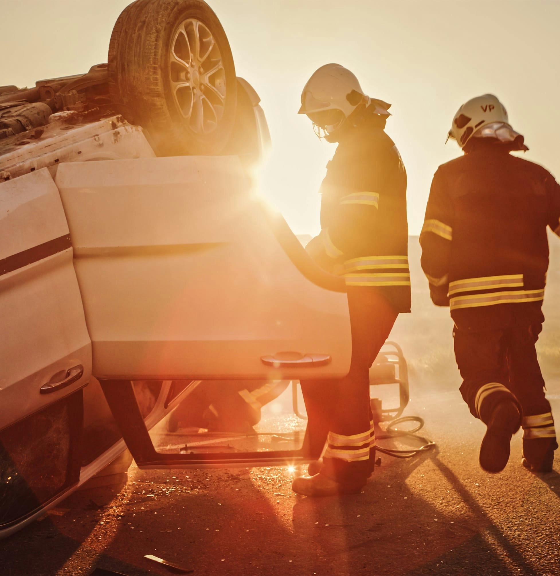 firefighters are working on a car that is sitting on top of a hill