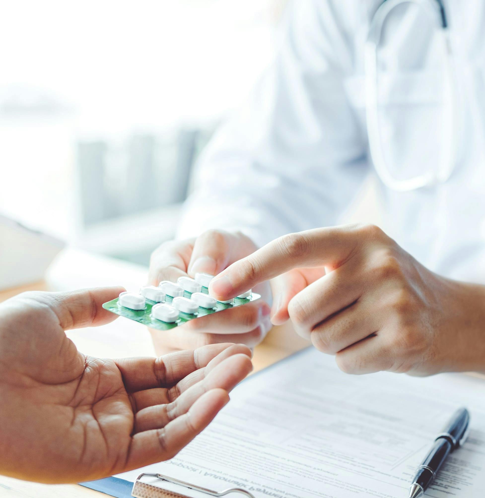 someone is holding a pill in their hand and a doctor is holding a pill