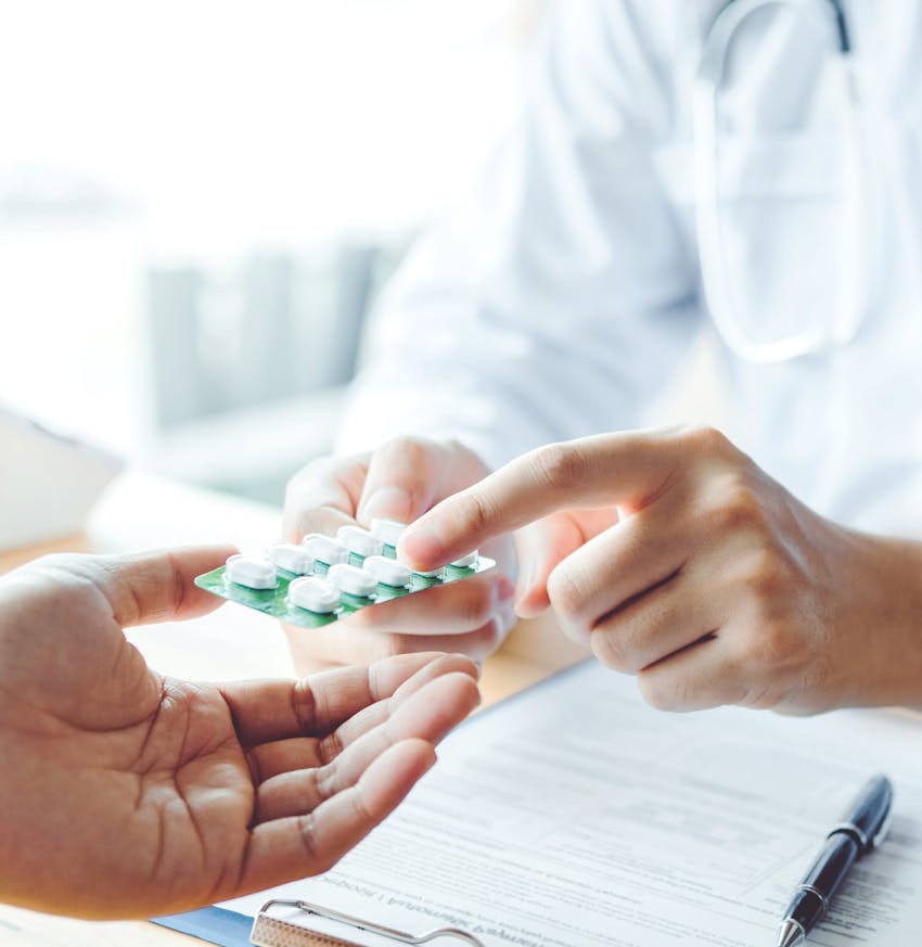 someone is holding a pill in their hand and a doctor is holding a pill