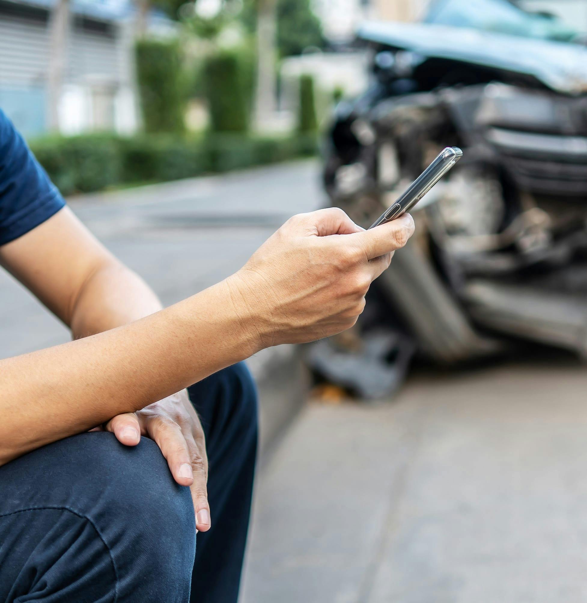 Person calling on their phone in front of a car wreck