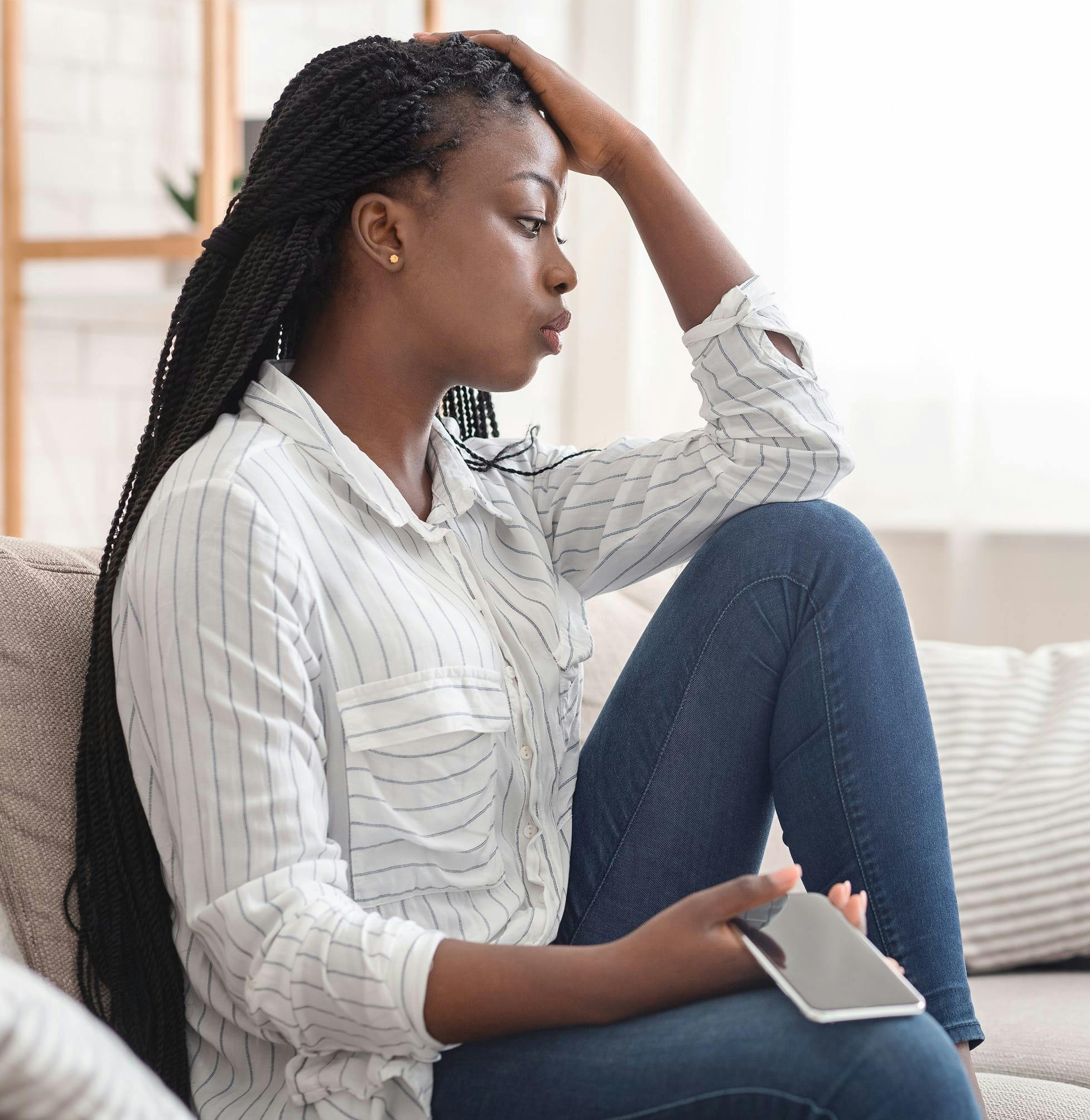 Woman holding her head on her couch