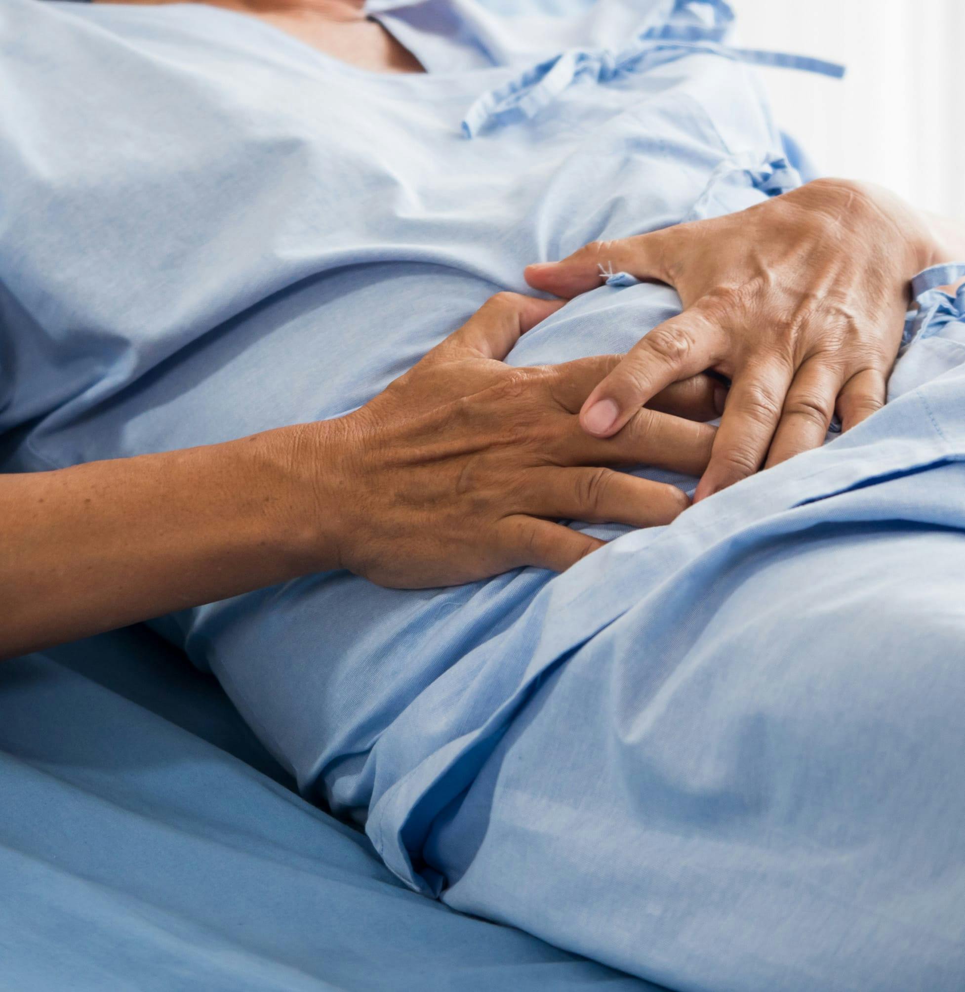 Person holding their stomach in a hospital bed