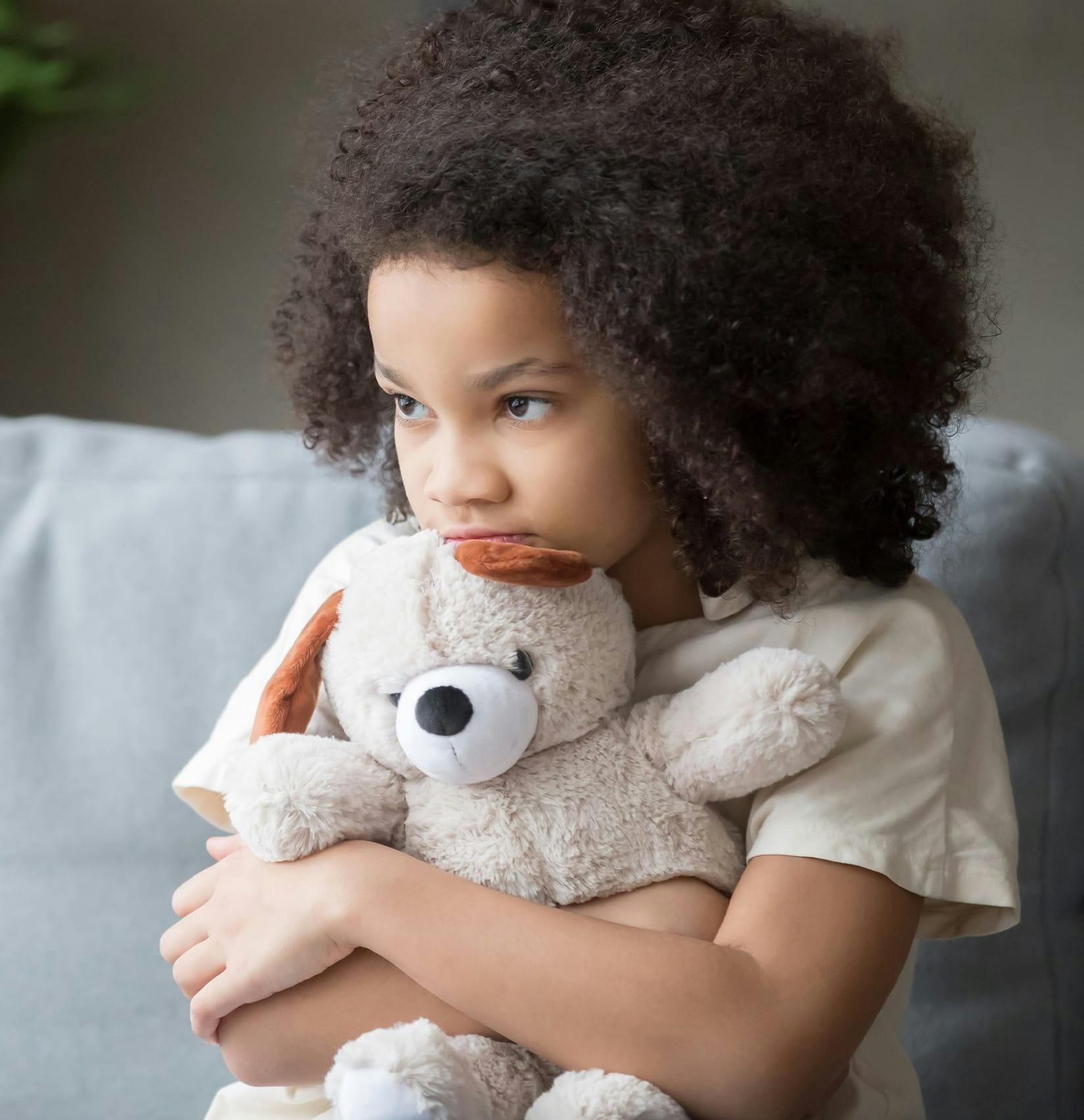 Little girl holding onto her teddy bear.