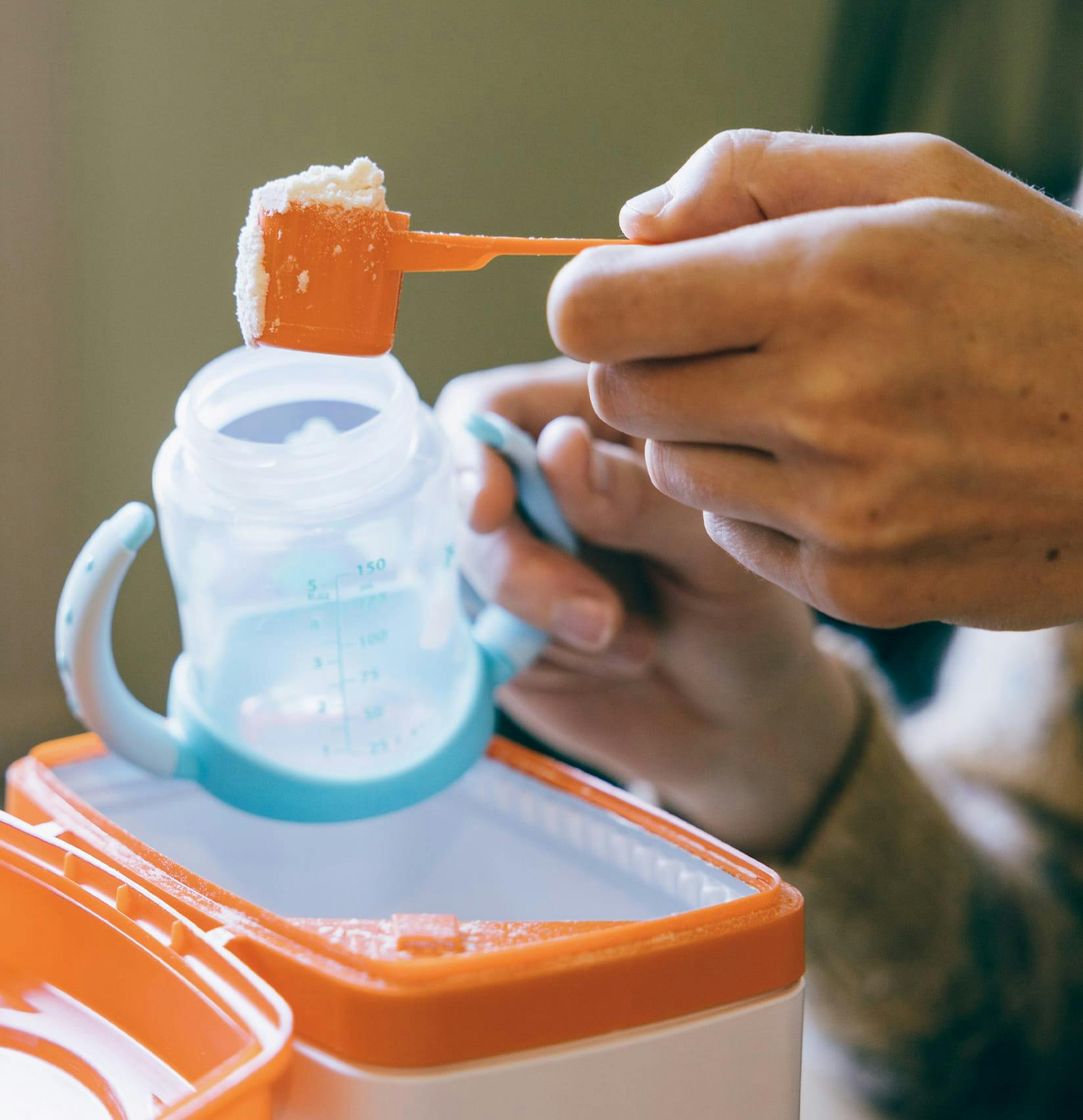 Person scooping baby formula into a bottle