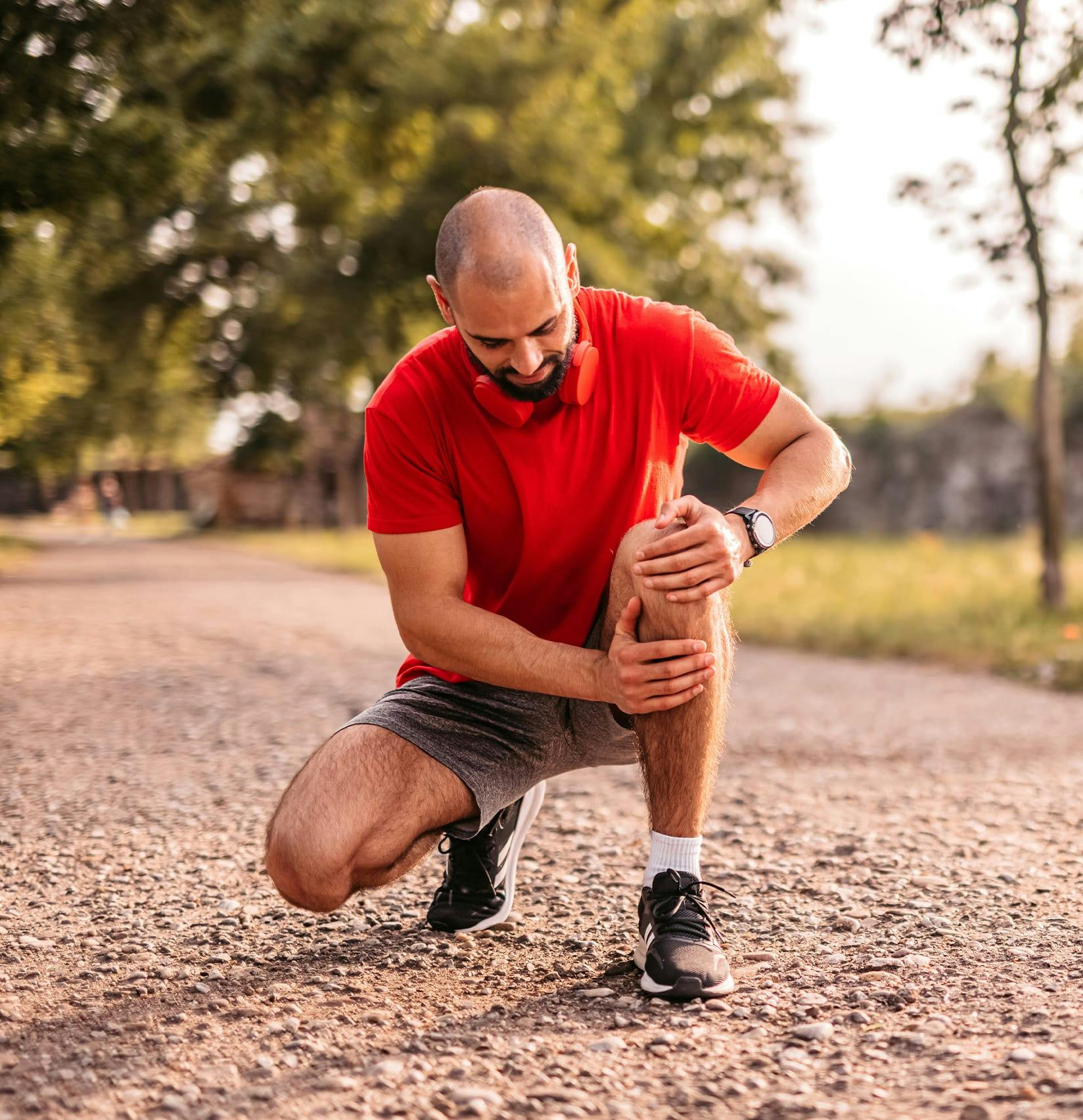 Man outside holding his knee