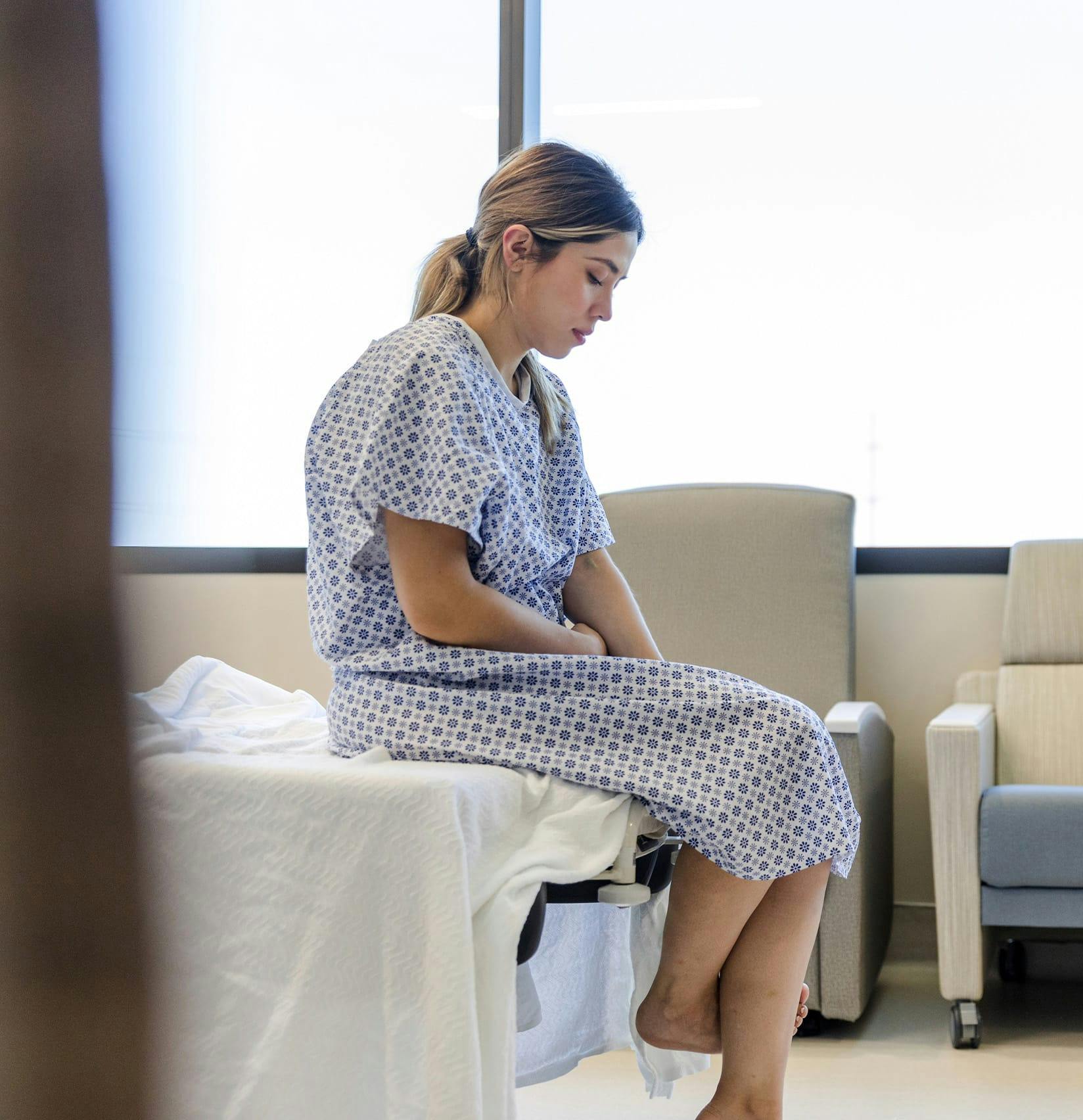 Woman stressed out in a hospital bed and gown