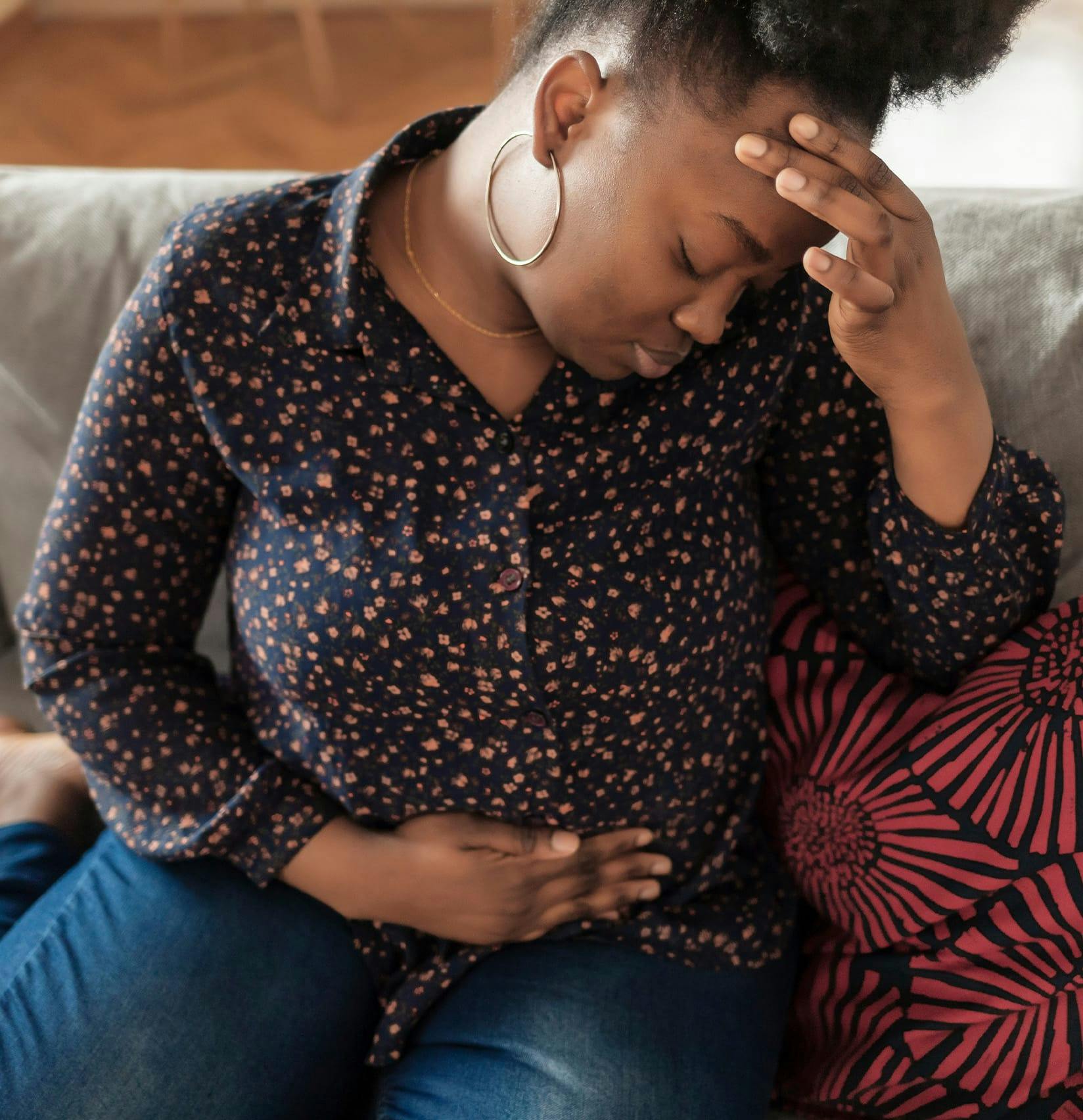 Woman holding her stomach and head