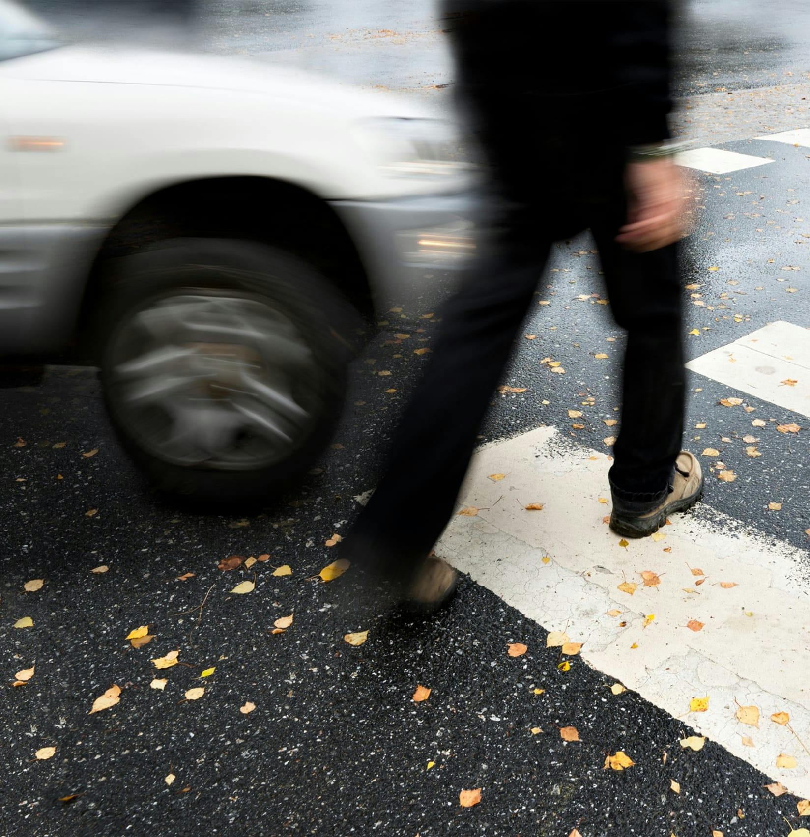 person crossing crosswalk in front of a car