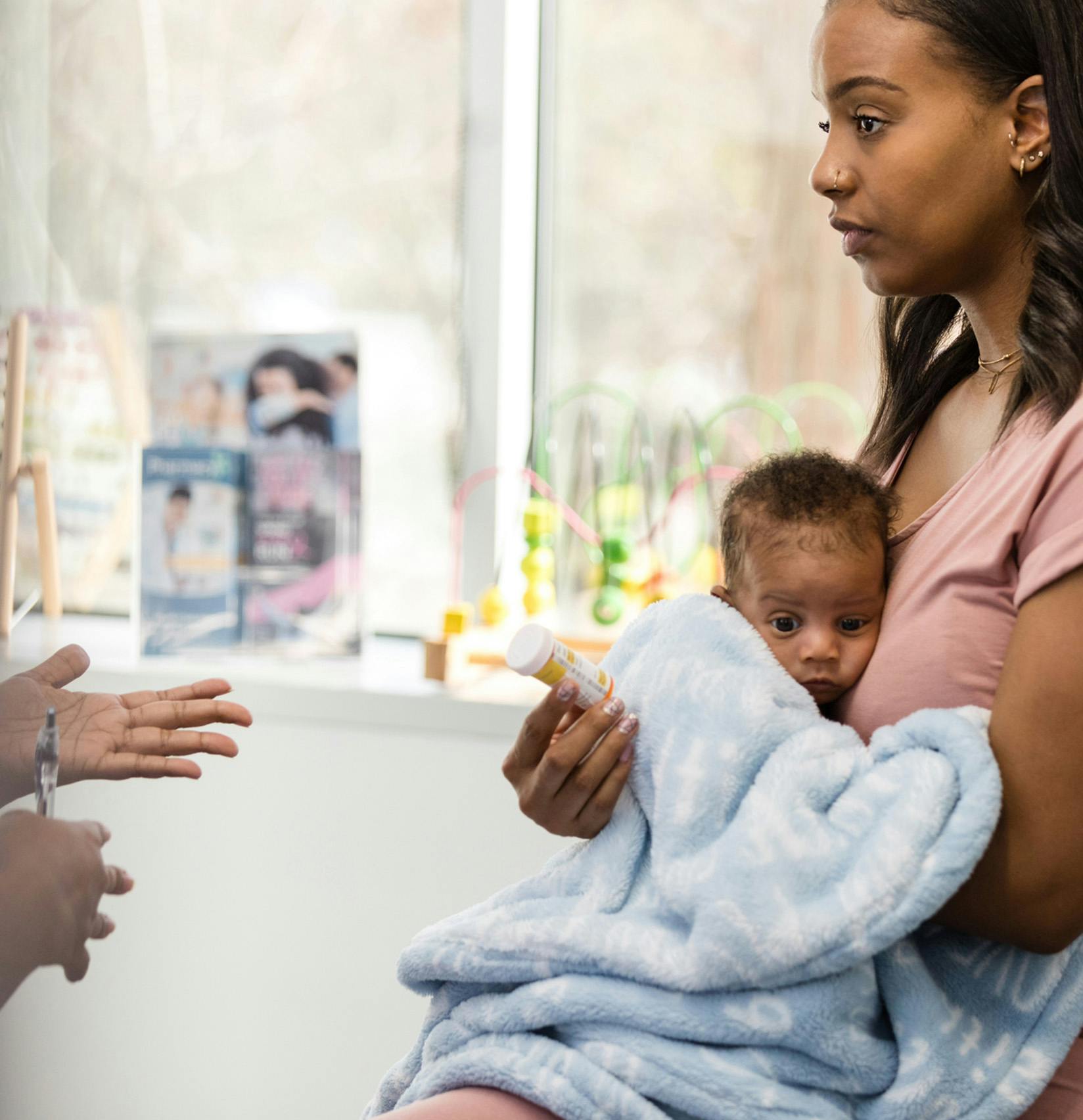 Woman holding her baby and looking at medicine