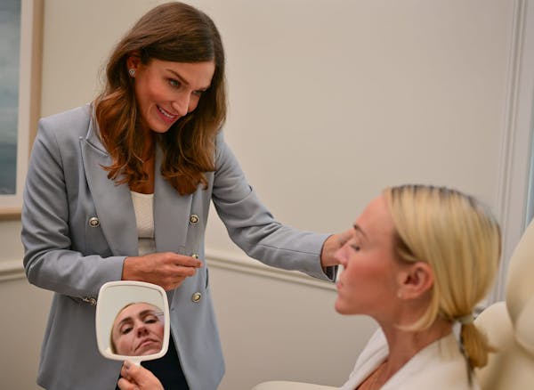 patient holding a mirror to her face while Dr. Smith points