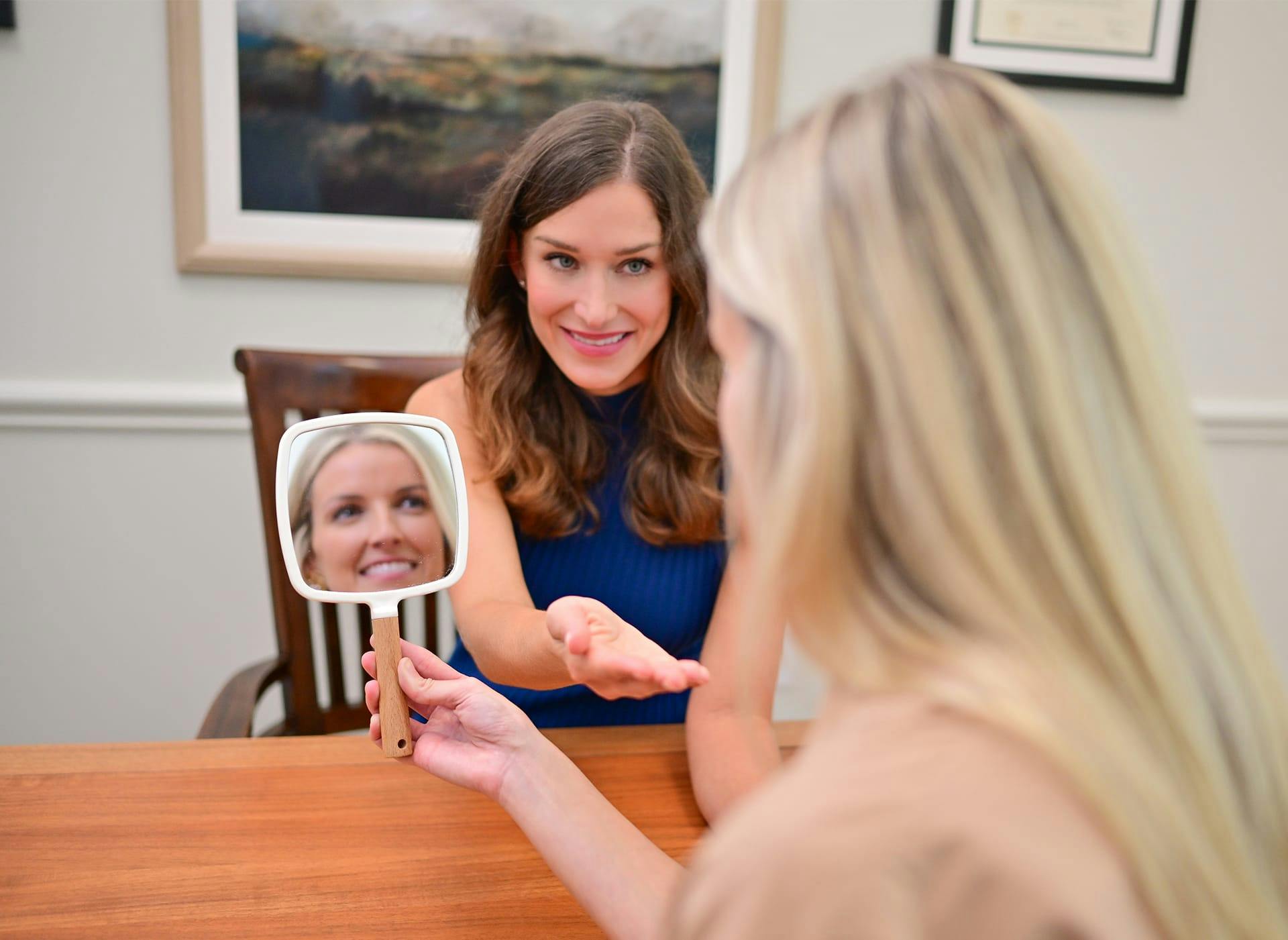 woman looking at her face in a handheld mirror