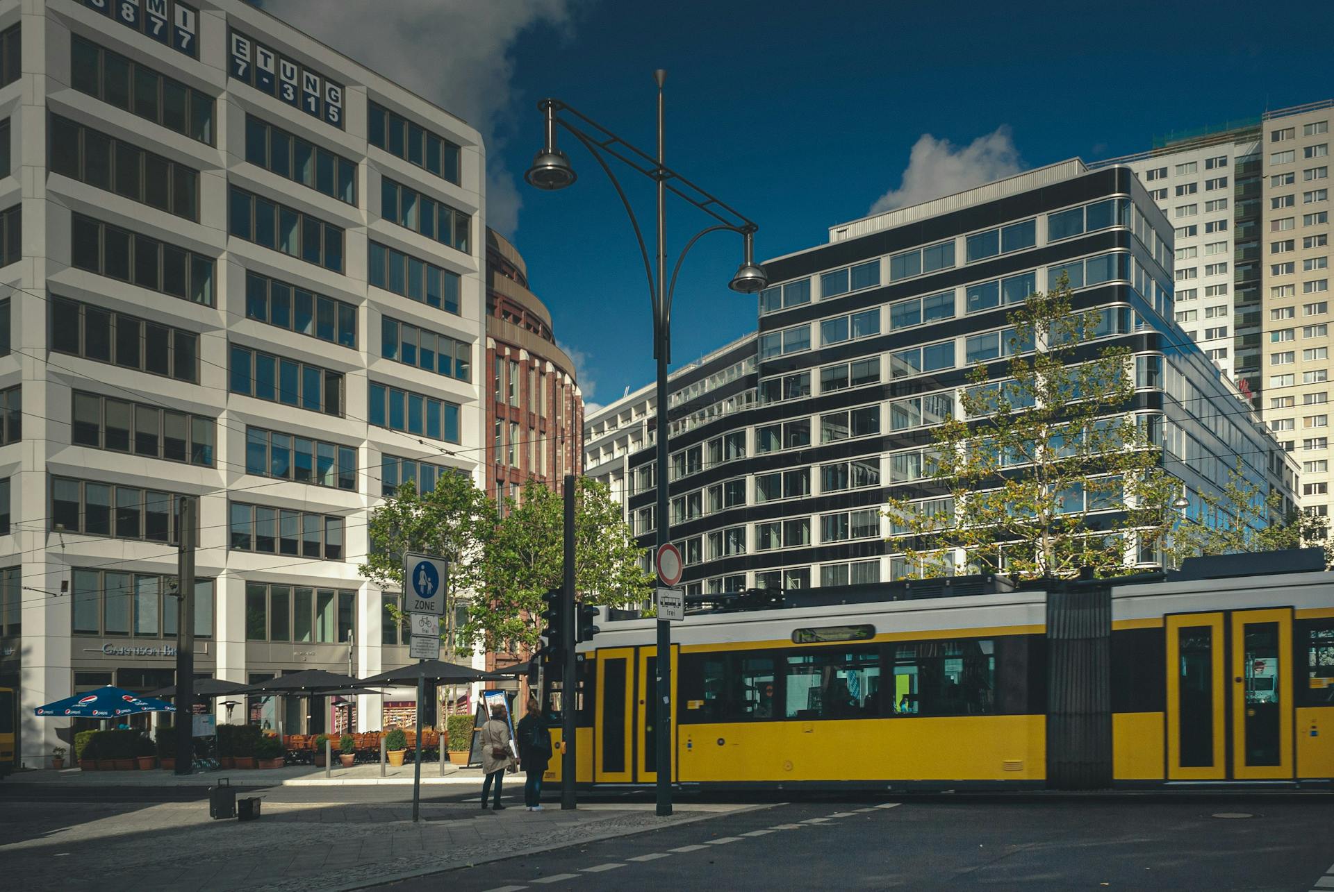 Berliner Straßenkreuzung mit gelber Straßenbahn und modernen Bürogebäuden.