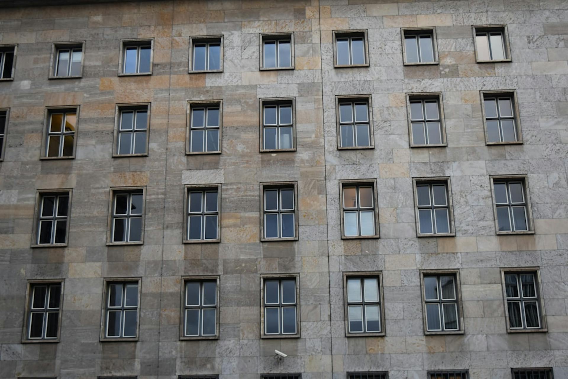 Apartment building facade with an even grid of stone panels and windows.