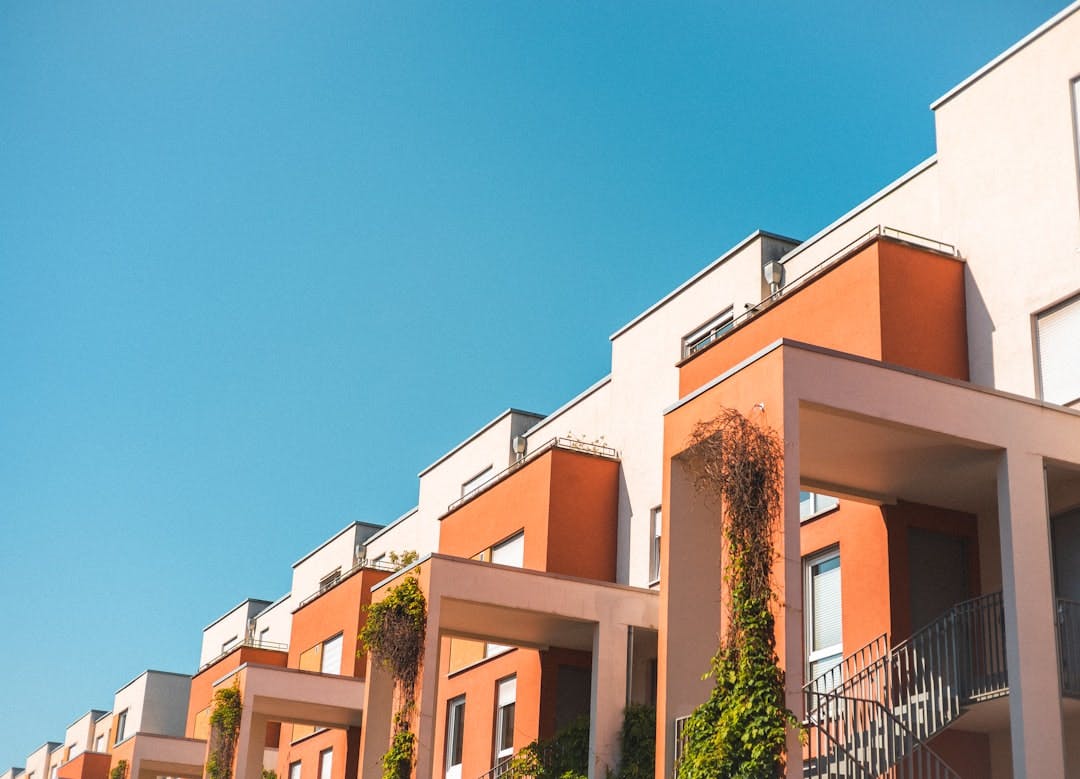 Row of modern apartment buildings with balconies and terraces under a blue sky.