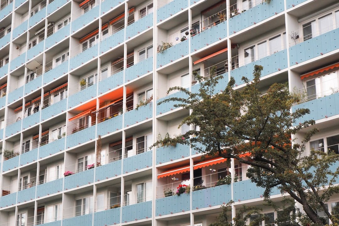 Hoher Wohnblock mit hellblauen Balkonverkleidungen und orangen Markisen.