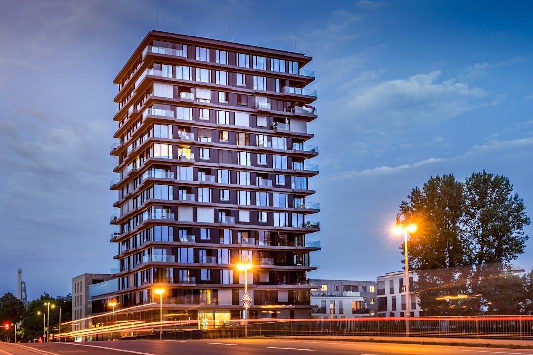 Modern high-rise building with illuminated balconies at dusk.