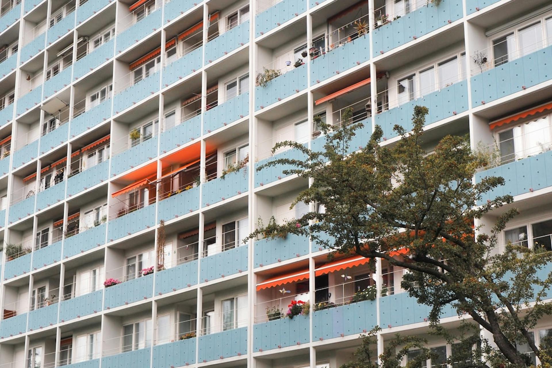 Large apartment high-rise with blue balcony panels and orange awnings.