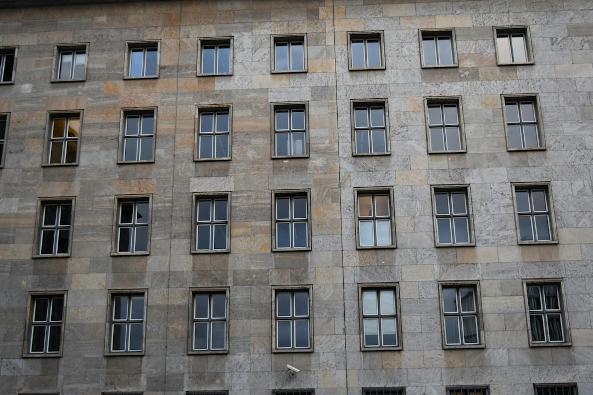 Fassade eines Wohnhauses mit einem gleichmäßigen Raster aus Steinplatten und Sprossenfenstern.