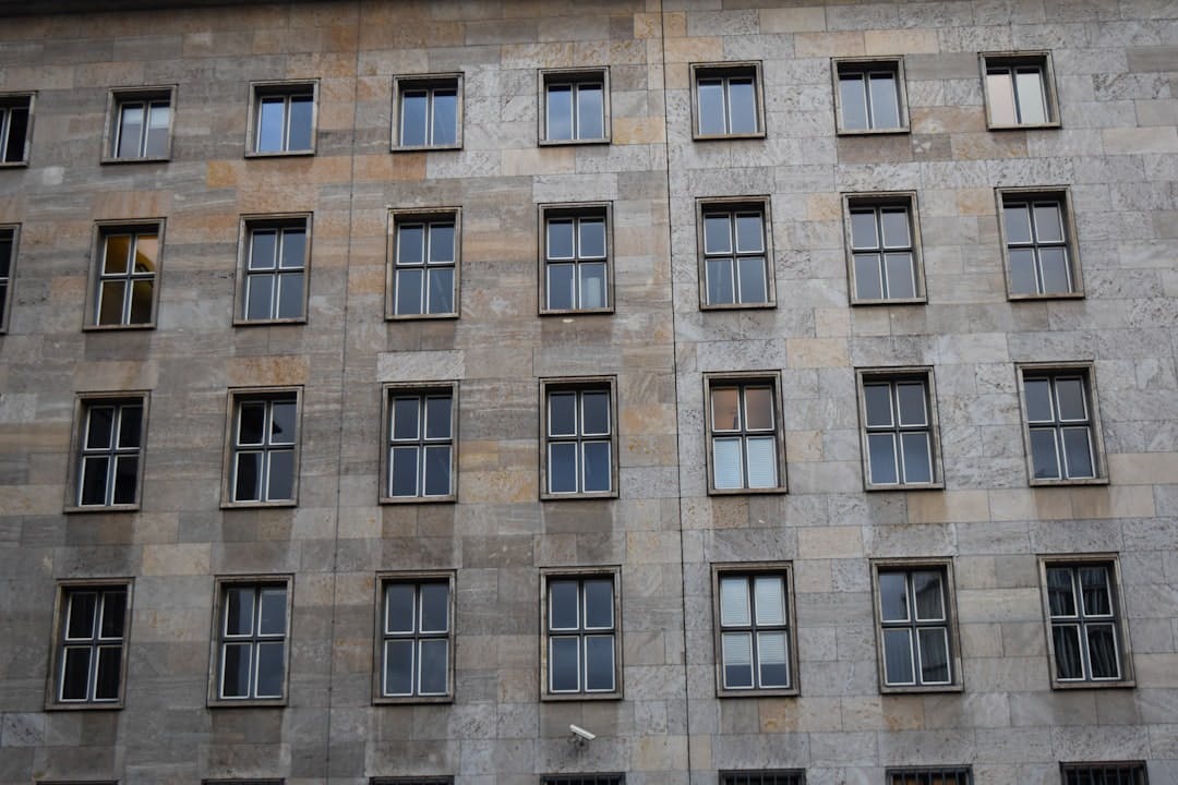 Fassade eines Wohnhauses mit einem gleichmäßigen Raster aus Steinplatten und Sprossenfenstern.