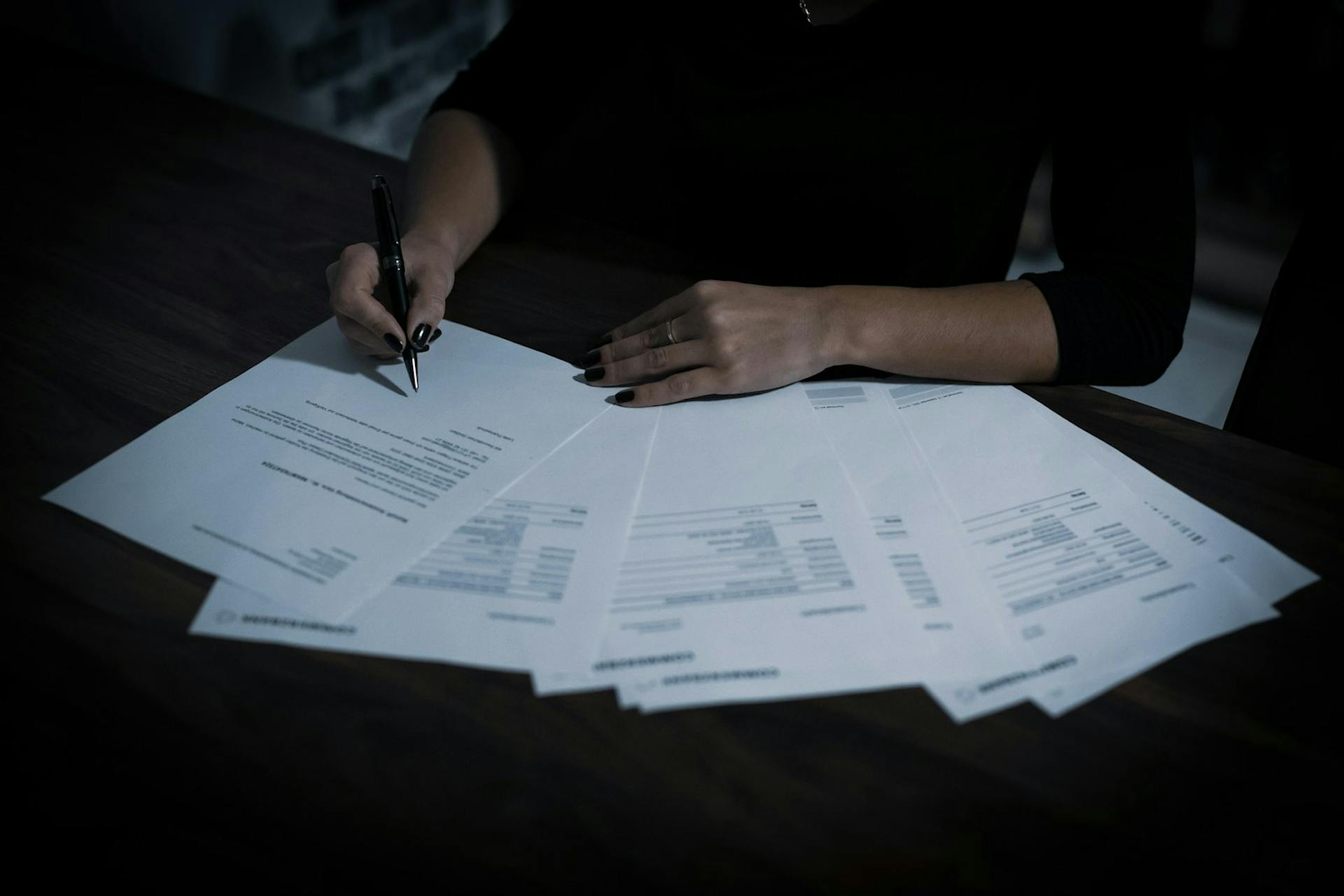 Person signing documents at a desk.