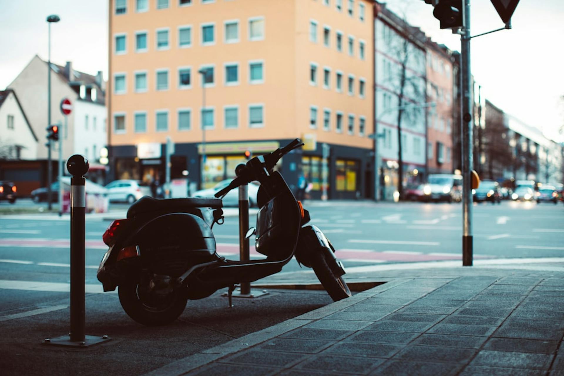 A parked scooter at a street corner in a German city neighborhood.