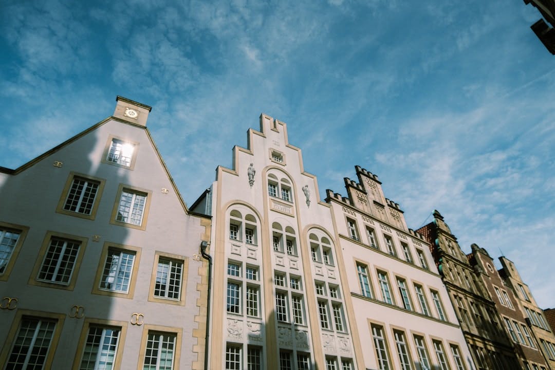 Historische Giebelfassaden am Prinzipalmarkt in Münster vor blauem Himmel.