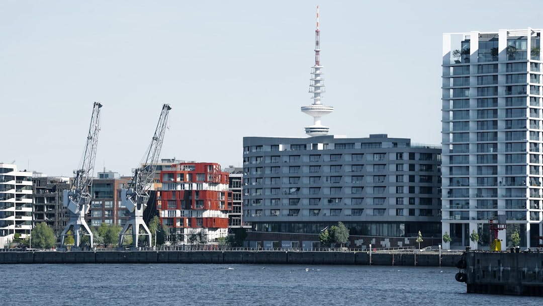 Modern residential buildings in Hamburg's HafenCity, with harbor cranes and the TV tower in the background.