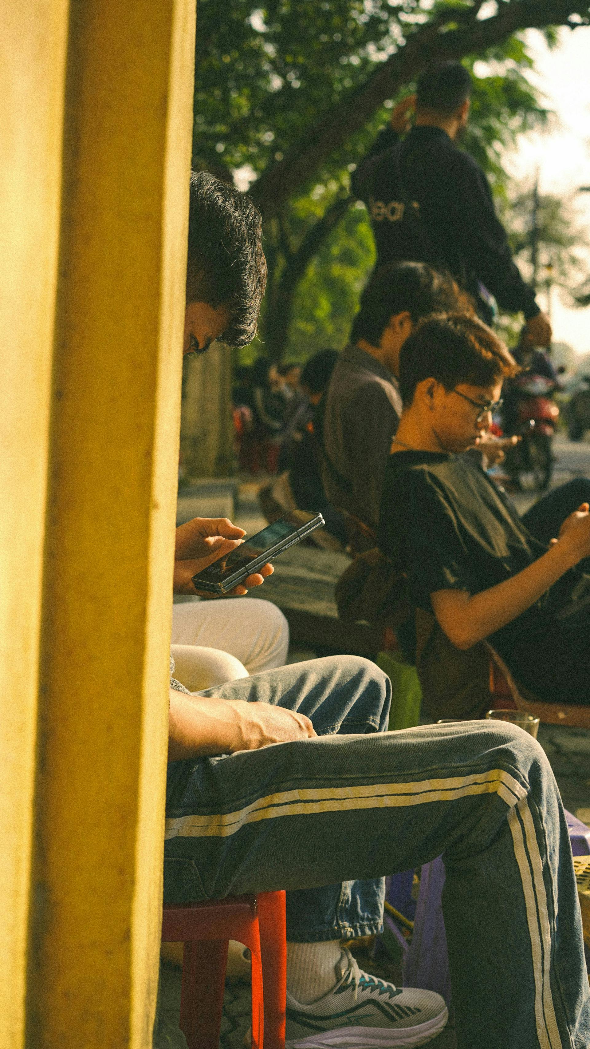 Junge Menschen prüfen draußen ihr Handy (Photo by Nhung Le on Unsplash)