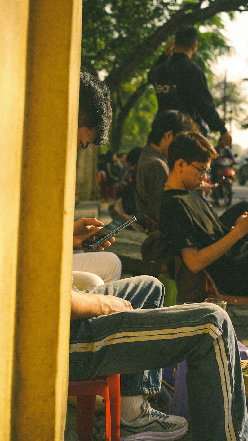 Junge Menschen prüfen draußen ihr Handy (Photo by Nhung Le on Unsplash)