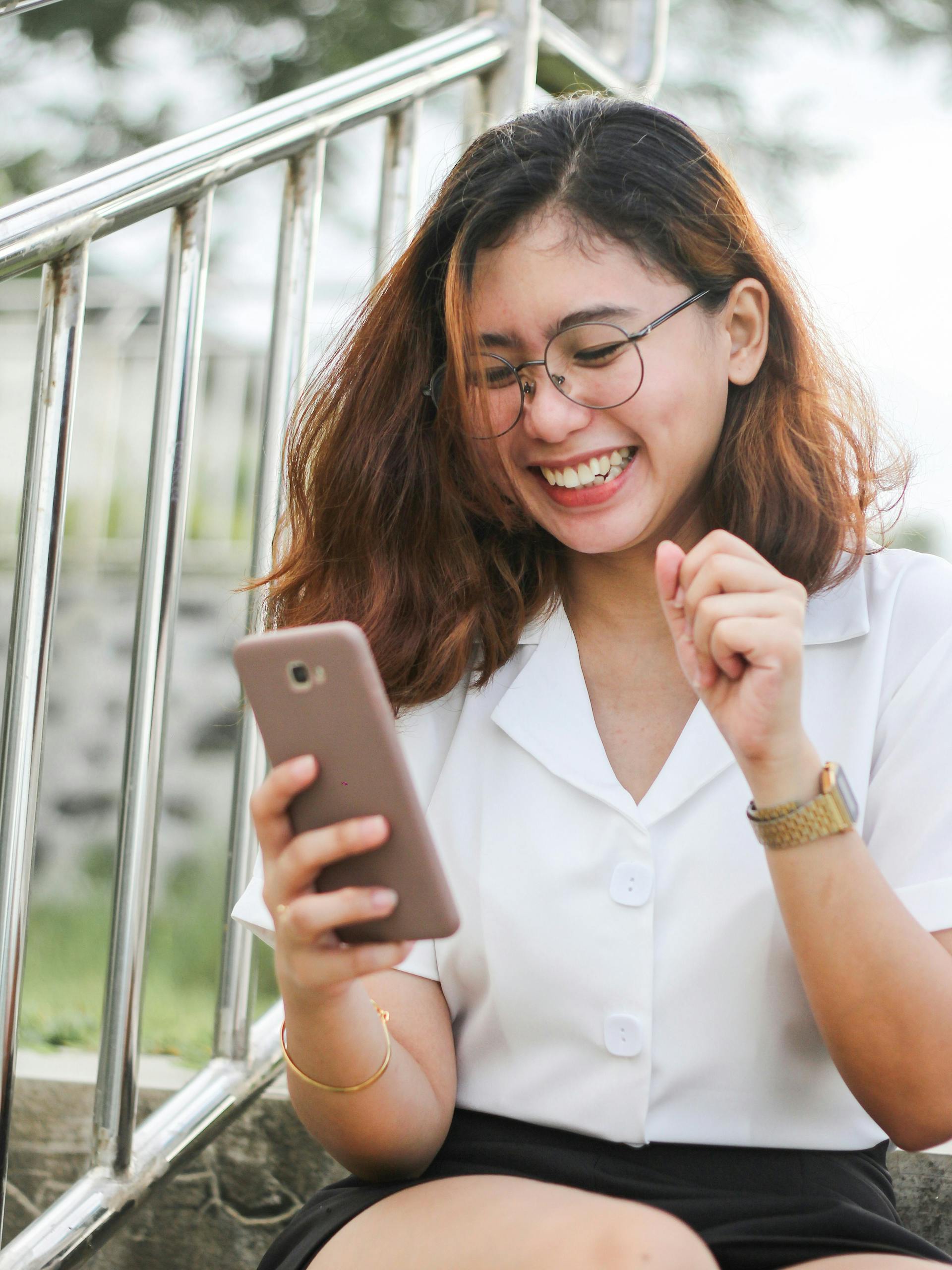 Junge Frau lacht beim Blick auf ihr Smartphone (Photo by Ghen Mar Cuaño on Unsplash)