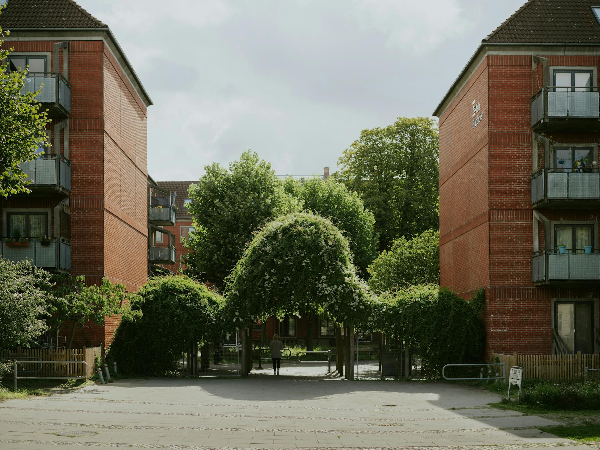 To røde murstensejendomme med boliger set fra gårdsiden (Photo by Yohan Marion on Unsplash)