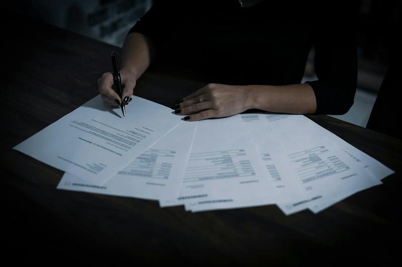 Woman sorting paperwork for a rental application at a table (Photo by Dimitri Karastelev on Unsplash)