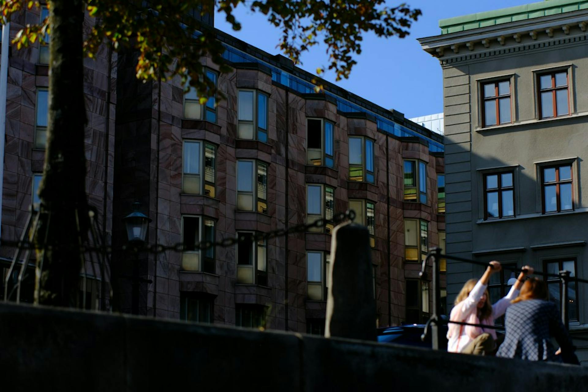 Mennesker sidder på en mur foran byejendomme