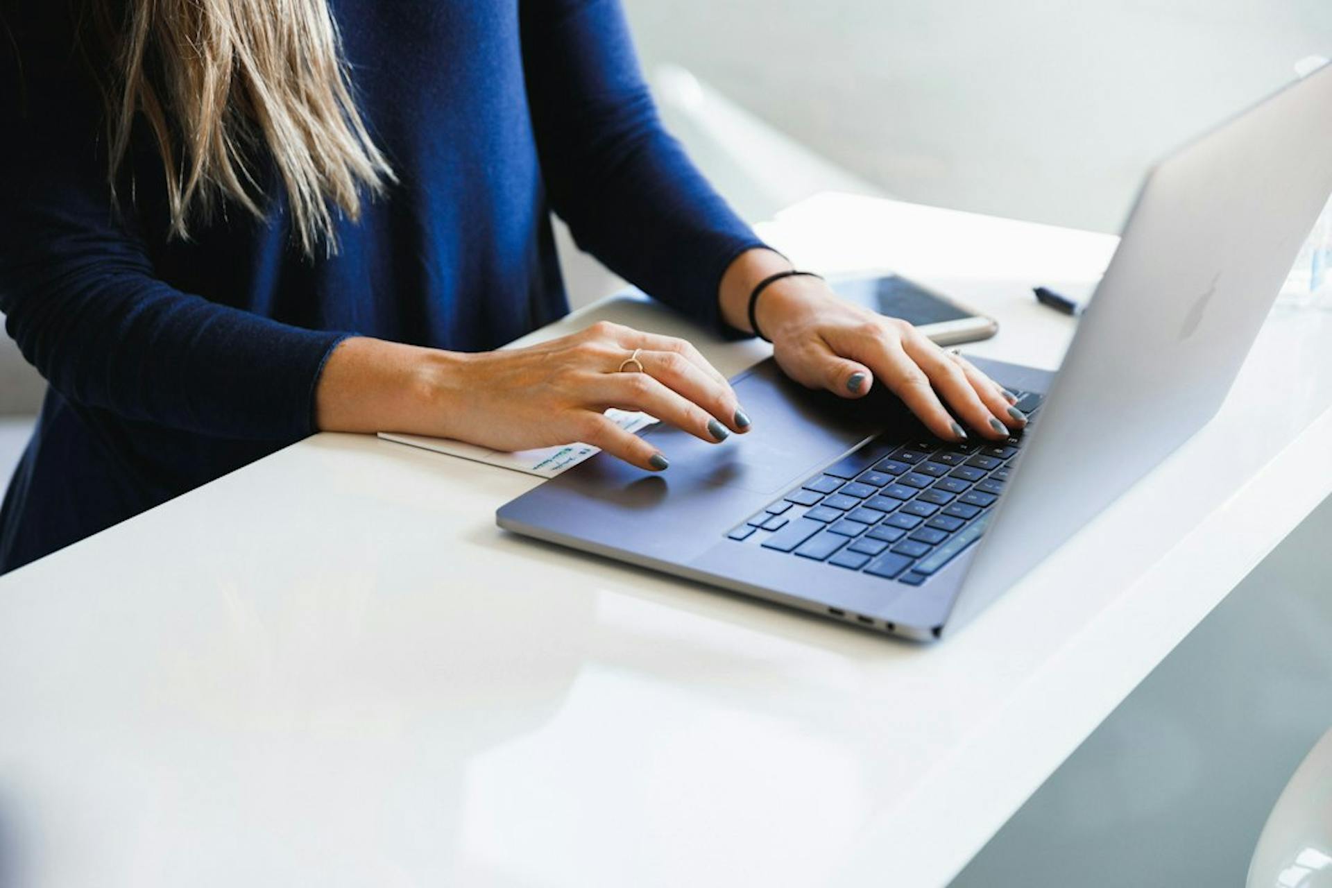 Kvinde i blå bluse arbejder på en bærbar computer
