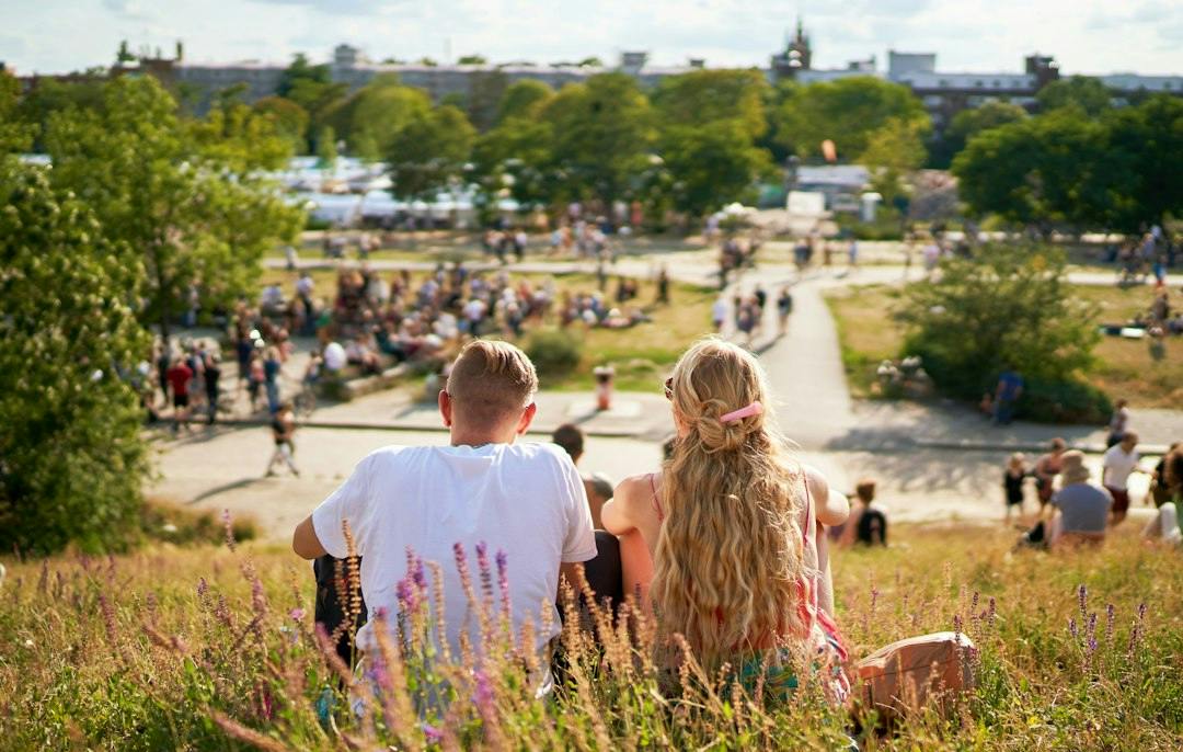 Junges Paar sitzt an einem Sommersonntag im Gras im Mauerpark in Prenzlauer Berg, Berlin (Photo by Norbert Braun on Unsplash)