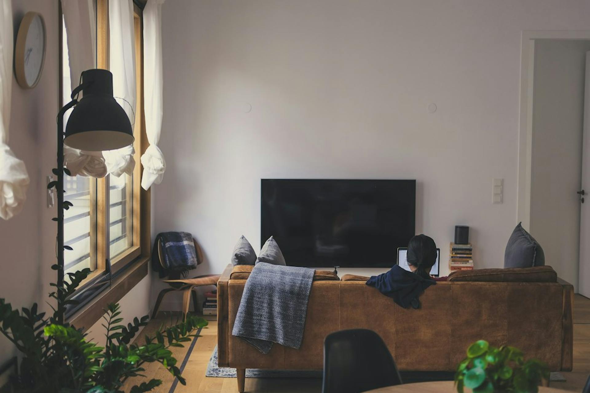 Person entspannt mit Laptop auf dem Sofa einer hellen möblierten Wohnung (Photo by Grant on Unsplash)