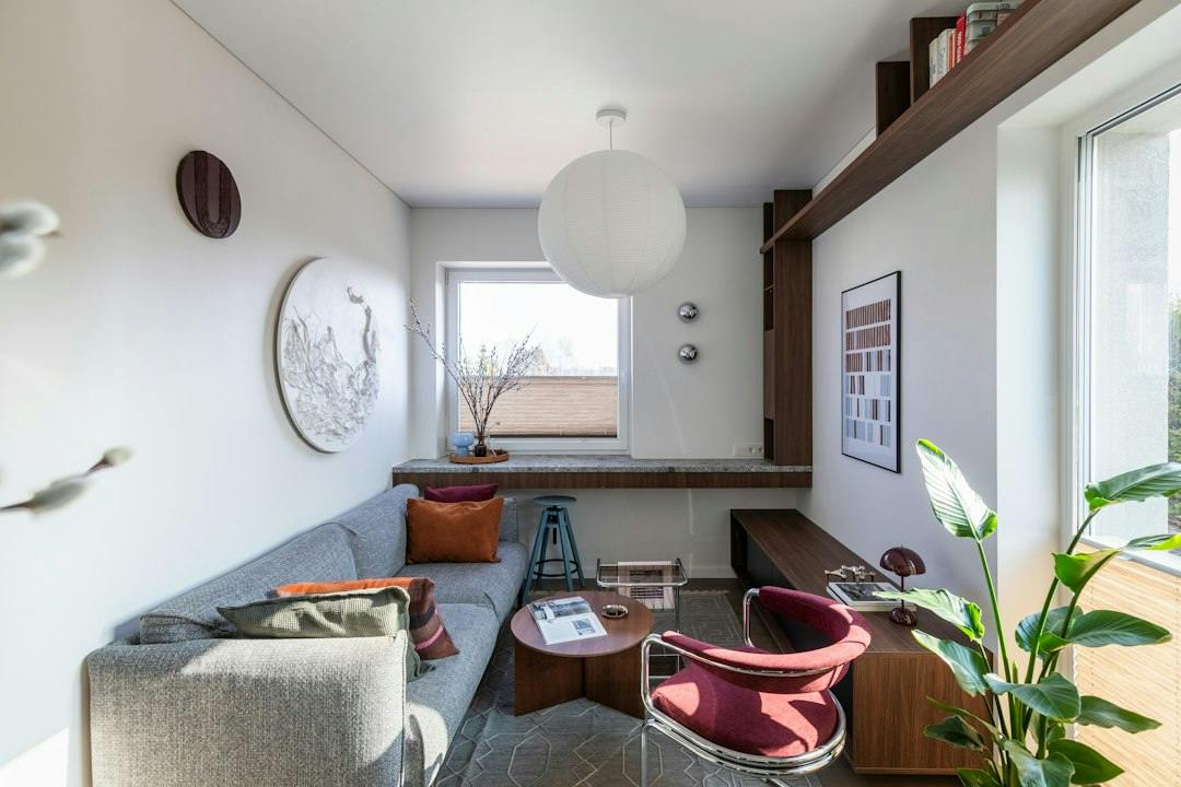 Compact, bright living room with a sofa, armchair and shelves in a small apartment (Photo by Irena Oze on Unsplash)