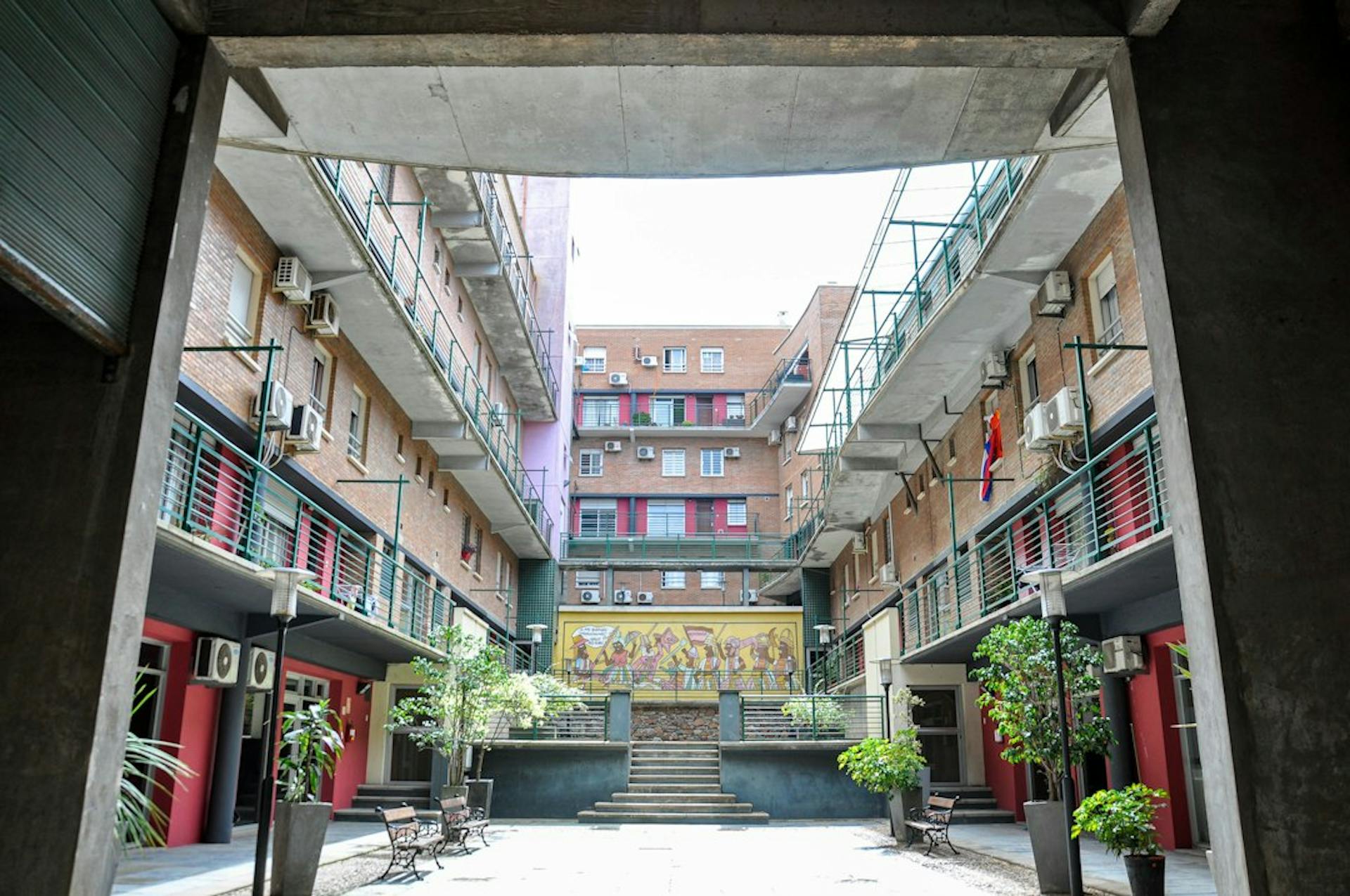 Courtyard of an apartment building with balconies and potted plants (Photo by Nikolai Kolosov on Unsplash)